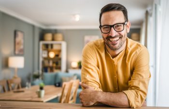 One man adult caucasian male with beard and eyeglasses stand at home happy smile copy space